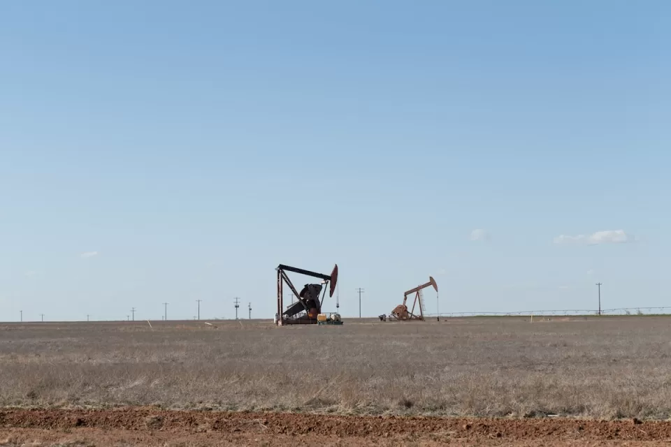 Two oil drilling derricks in vast field in West Texas.